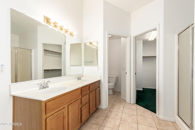 bathroom featuring toilet, a walk in closet, a sink, and tile patterned flooring