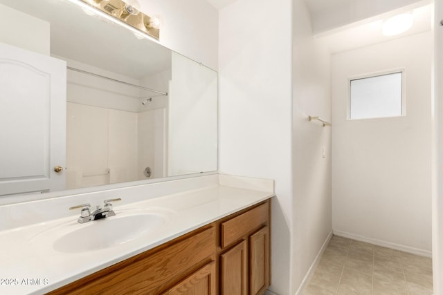 bathroom featuring vanity, baseboards, and walk in shower