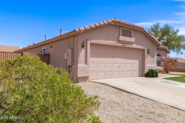 view of property exterior featuring fence, a garage, stucco siding, concrete driveway, and a tiled roof