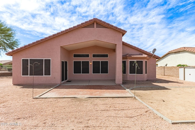 back of house featuring fence, stucco siding, a patio area, and a tile roof