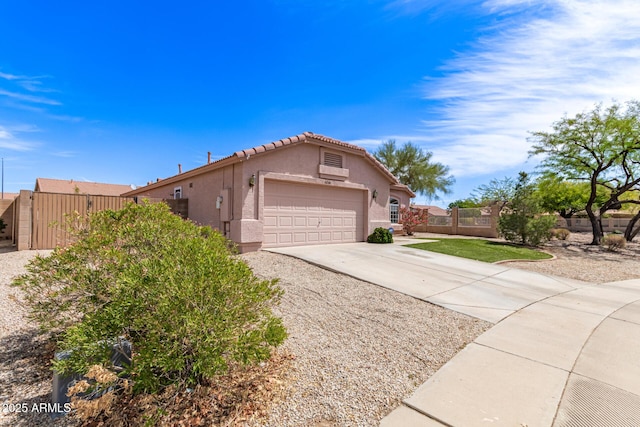 view of side of home featuring driveway, a tile roof, a garage, fence, and stucco siding