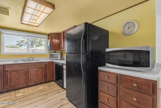 kitchen with sink, light hardwood / wood-style flooring, and black appliances