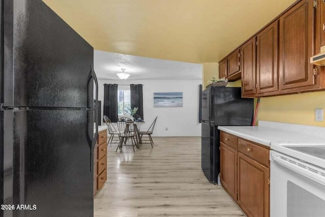 kitchen featuring white electric stove, black refrigerator, and light wood-type flooring