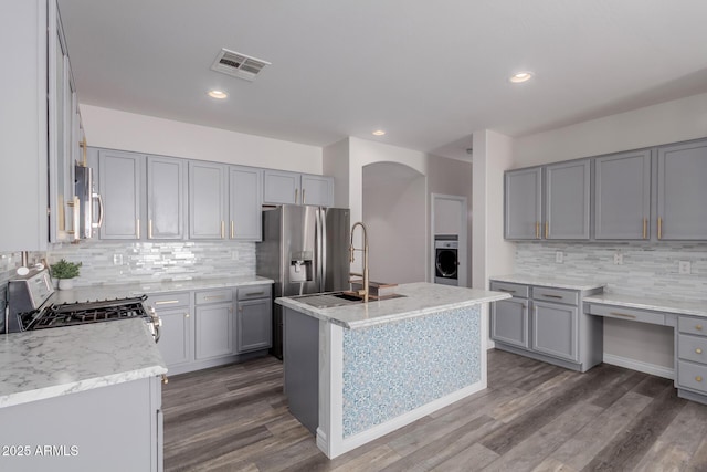 kitchen with appliances with stainless steel finishes, dark hardwood / wood-style floors, an island with sink, sink, and gray cabinetry