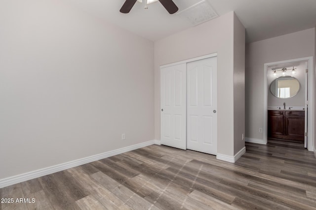 unfurnished bedroom with sink, wood-type flooring, a closet, and ceiling fan