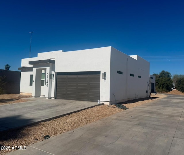 view of front of property featuring an attached garage, driveway, and stucco siding