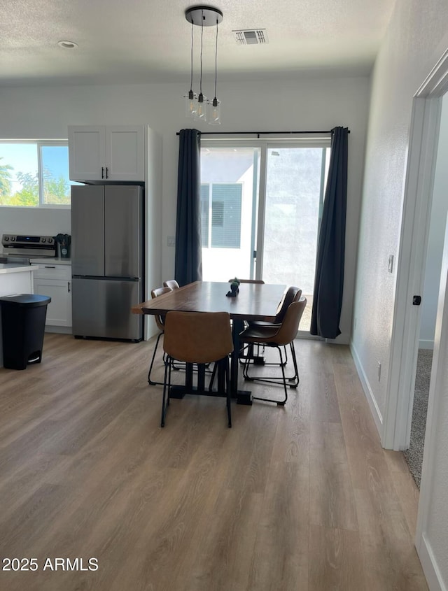 dining area with light wood-style floors, plenty of natural light, and visible vents