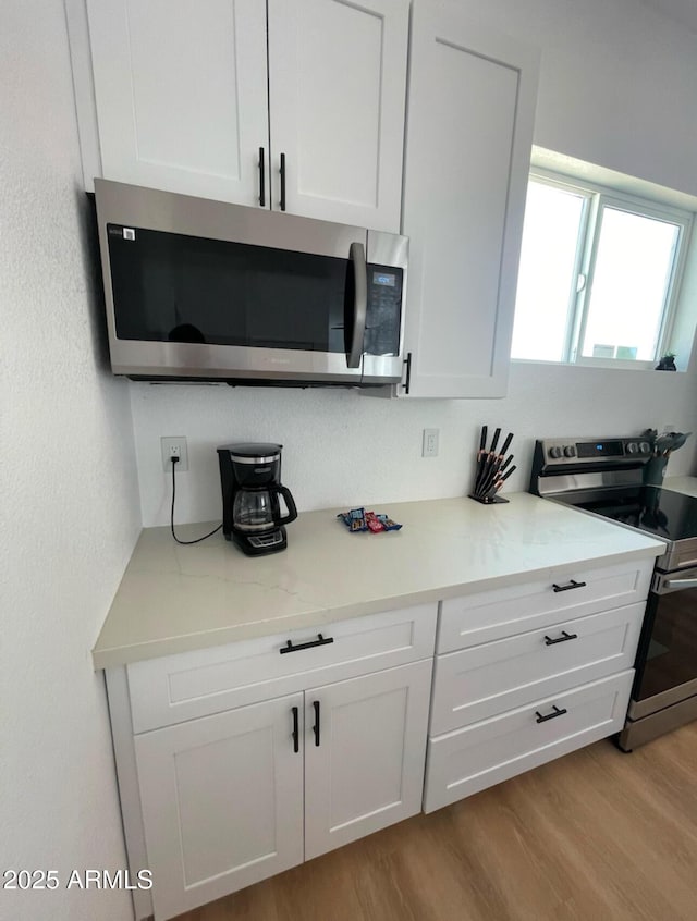 kitchen with light wood-style flooring, white cabinetry, and stainless steel appliances