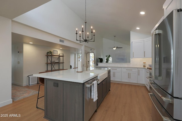 kitchen featuring stainless steel appliances, light countertops, white cabinets, a kitchen island, and a kitchen breakfast bar