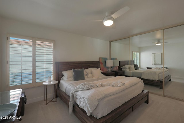 bedroom with light carpet, baseboards, a ceiling fan, and a closet