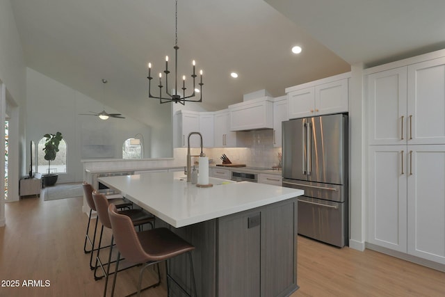 kitchen featuring a kitchen island with sink, appliances with stainless steel finishes, open floor plan, and white cabinetry