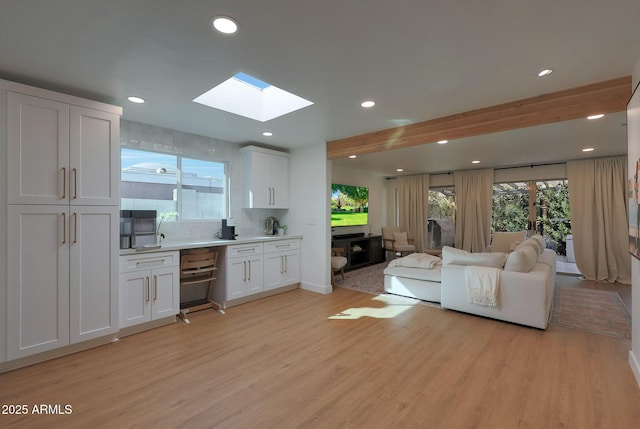 living room with a healthy amount of sunlight, a skylight, light wood-style flooring, and recessed lighting