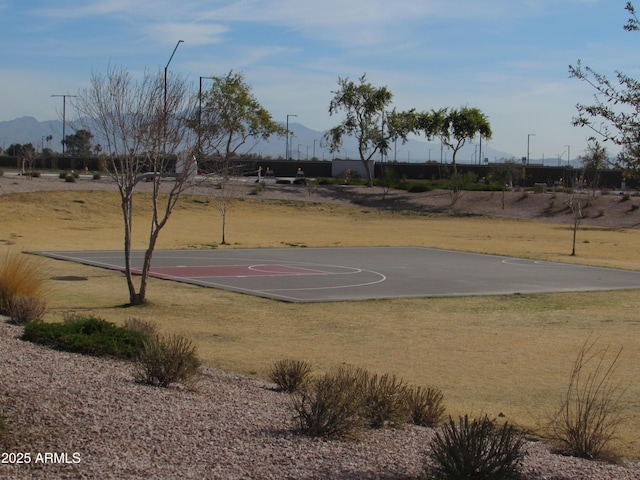 view of sport court with a mountain view and a yard