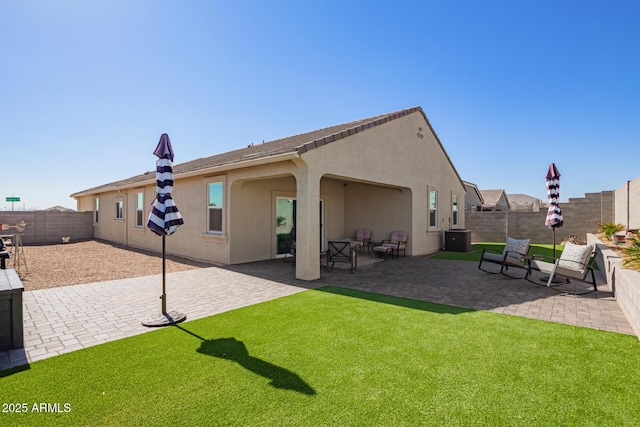 back of property featuring central AC unit, a lawn, and a patio