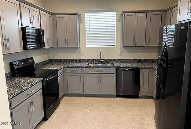 kitchen featuring black appliances, sink, gray cabinets, dark stone countertops, and light tile patterned floors