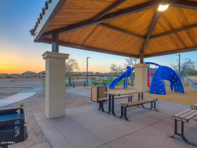 patio terrace at dusk featuring a gazebo and a playground