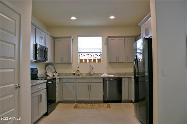 kitchen featuring gray cabinetry, light stone countertops, sink, light tile patterned flooring, and black appliances