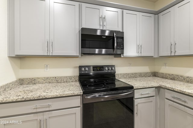 kitchen with light stone counters and appliances with stainless steel finishes