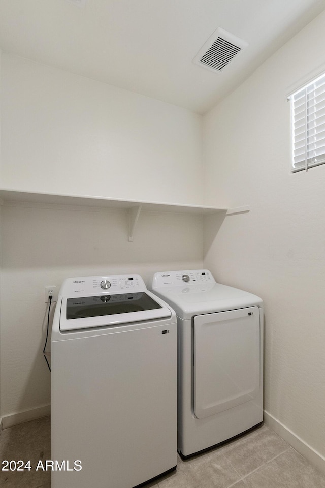 washroom with washing machine and dryer and light tile patterned floors