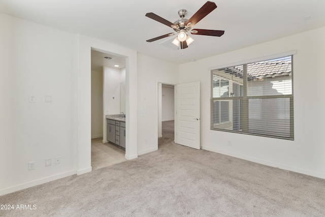 unfurnished bedroom with light carpet, ensuite bathroom, and ceiling fan