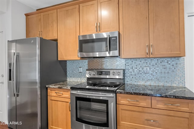 kitchen featuring stainless steel appliances, dark stone countertops, and tasteful backsplash