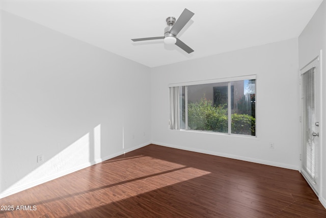unfurnished room featuring dark wood-style floors, ceiling fan, and baseboards