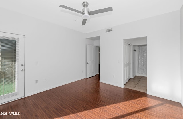 unfurnished room featuring a ceiling fan, wood finished floors, visible vents, and baseboards