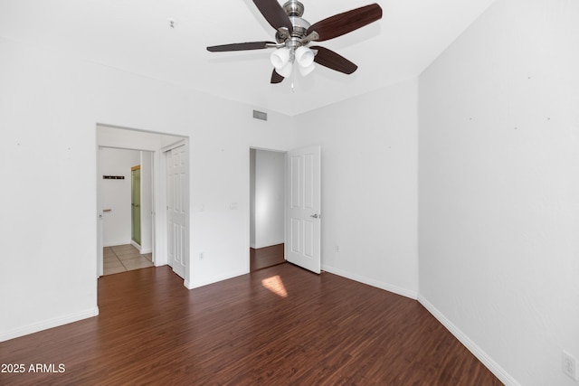 unfurnished bedroom featuring dark wood-style floors, baseboards, visible vents, and a ceiling fan