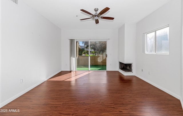 unfurnished living room featuring visible vents, baseboards, a ceiling fan, dark wood-style flooring, and a multi sided fireplace