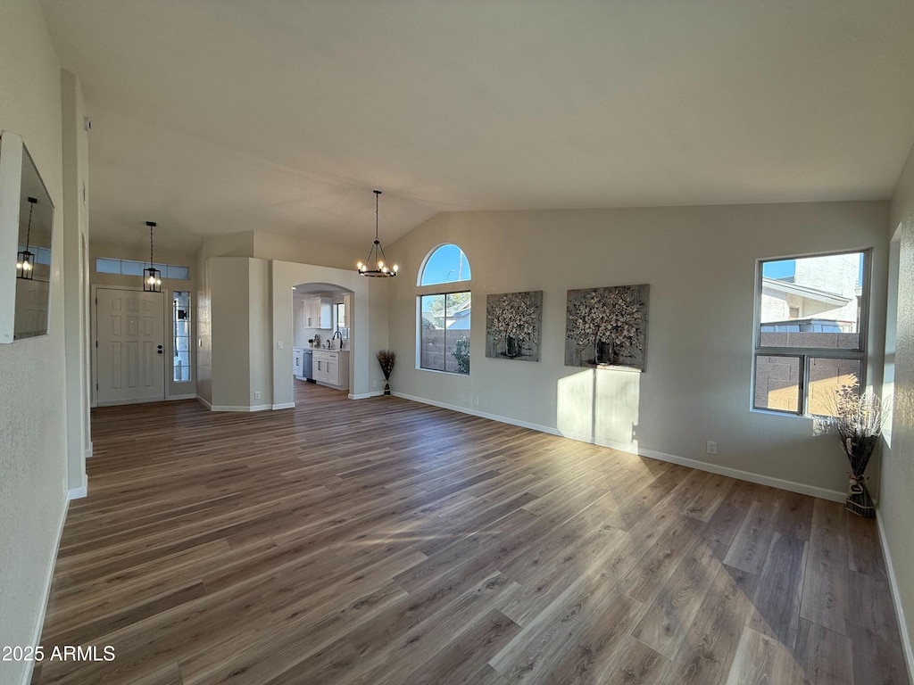 unfurnished living room featuring lofted ceiling, dark wood-type flooring, and a notable chandelier