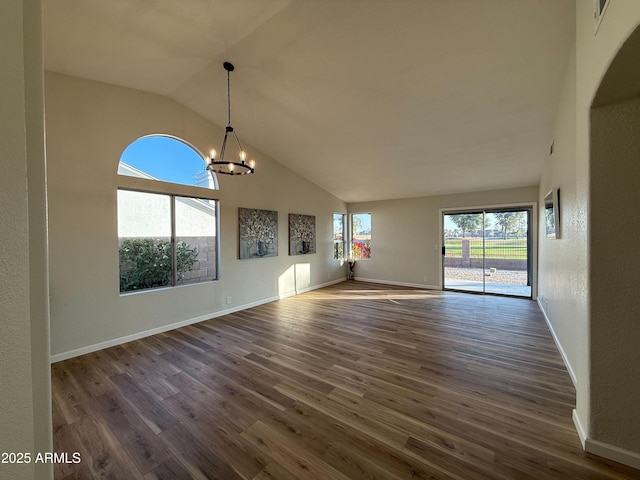 unfurnished living room with dark wood-type flooring, high vaulted ceiling, and an inviting chandelier