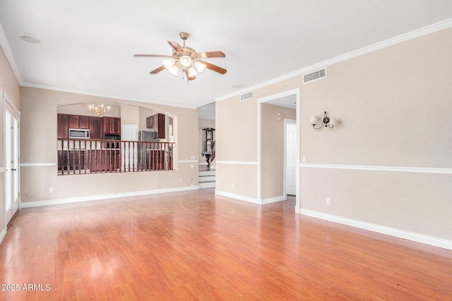 spare room featuring ceiling fan with notable chandelier, light hardwood / wood-style flooring, and ornamental molding