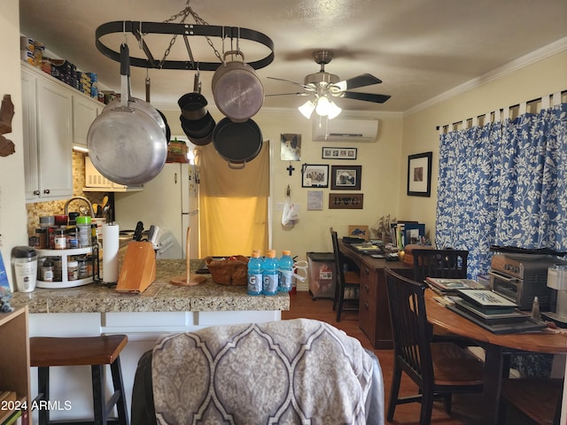 kitchen featuring an AC wall unit, ceiling fan, ornamental molding, dark hardwood / wood-style flooring, and white cabinetry