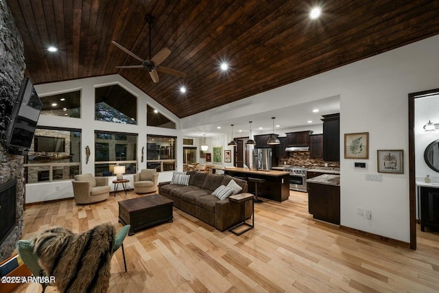 living room featuring high vaulted ceiling, a stone fireplace, light hardwood / wood-style flooring, and wooden ceiling