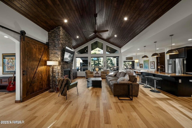 living room with sink, wood ceiling, high vaulted ceiling, a barn door, and light hardwood / wood-style floors