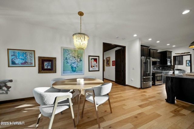 dining space with light hardwood / wood-style floors and a notable chandelier