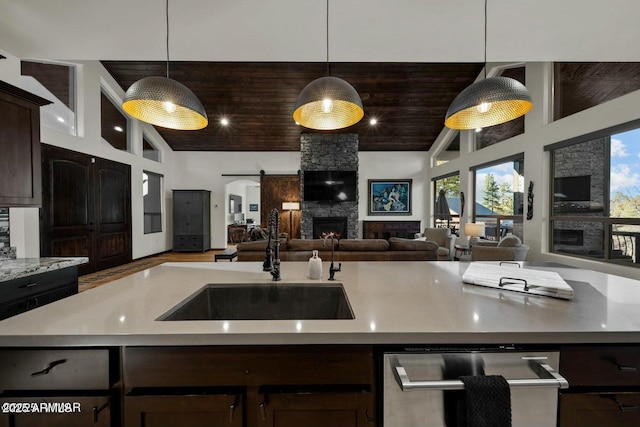 kitchen with pendant lighting, a fireplace, sink, and dark brown cabinets