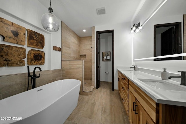 bathroom featuring vanity, independent shower and bath, hardwood / wood-style floors, and tile walls