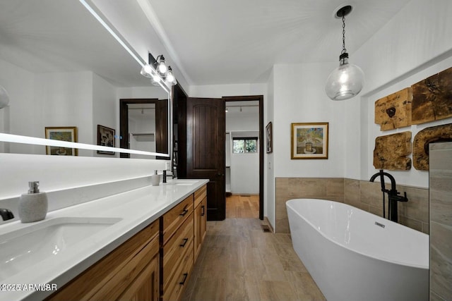 bathroom with vanity, wood-type flooring, tile walls, and a tub