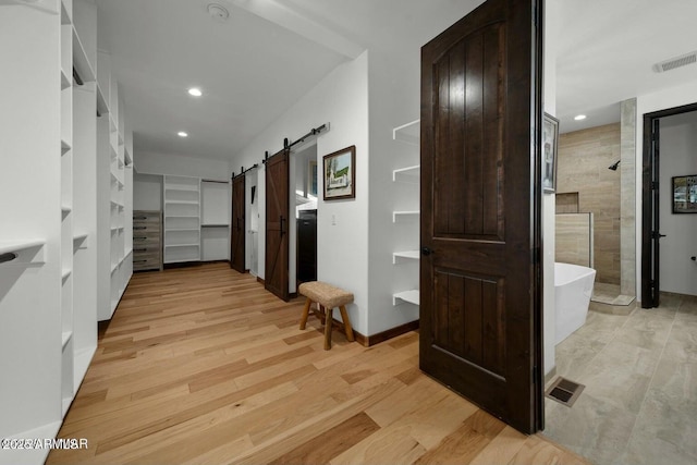 corridor with light hardwood / wood-style flooring and a barn door