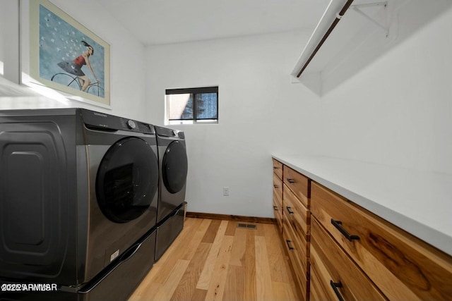 washroom with cabinets, washing machine and dryer, and light wood-type flooring