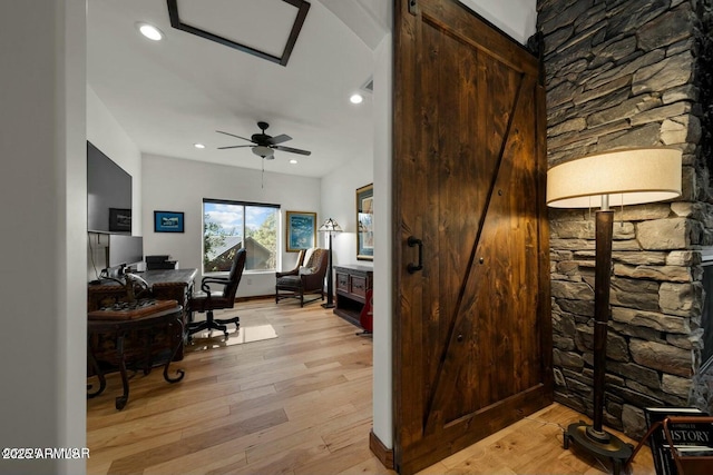 office space featuring ceiling fan, a barn door, and light hardwood / wood-style floors