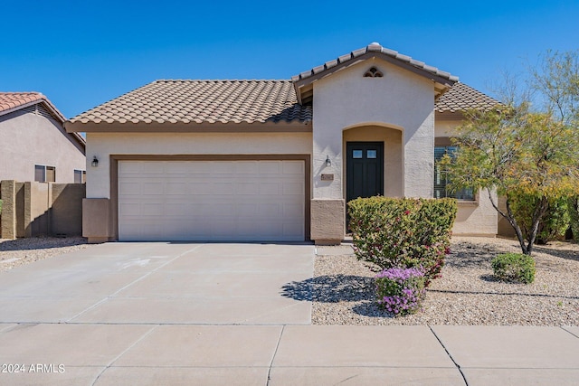 mediterranean / spanish house featuring a garage, a tile roof, driveway, and stucco siding