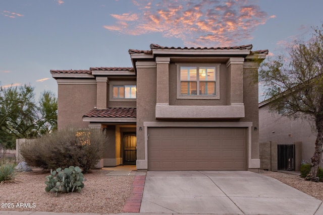 mediterranean / spanish house featuring a tiled roof, an attached garage, driveway, and stucco siding