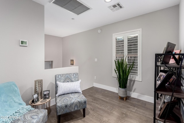 living area featuring visible vents, baseboards, and wood finished floors