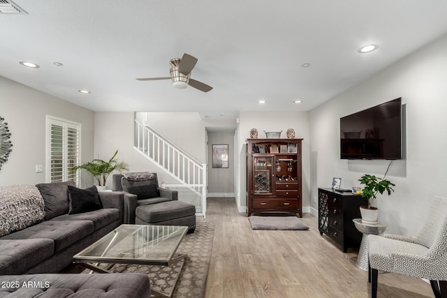 living room featuring light wood finished floors, visible vents, recessed lighting, and stairs