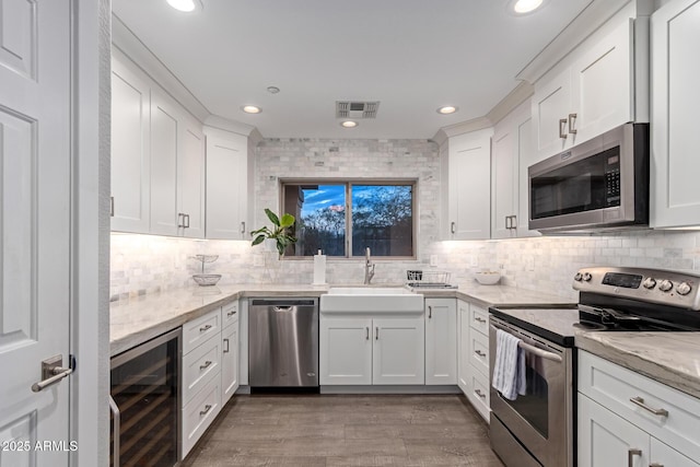 kitchen with visible vents, a sink, white cabinetry, wine cooler, and appliances with stainless steel finishes