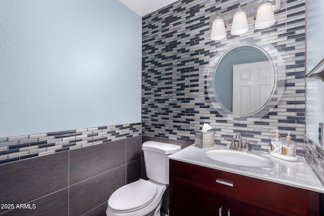 bathroom featuring vanity, tile walls, and toilet