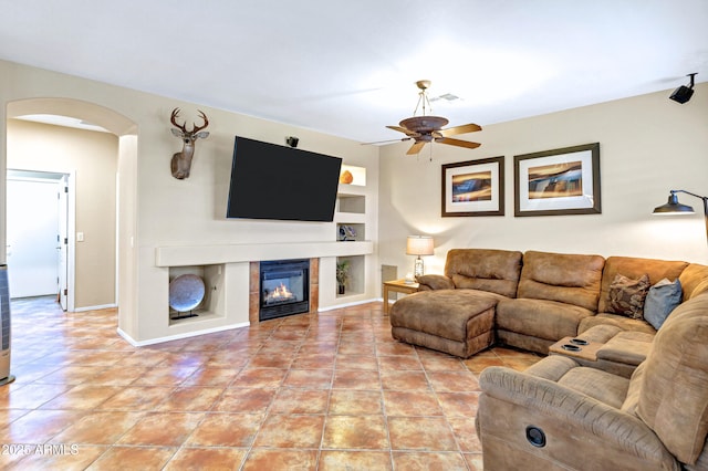 2758 N Sterling, Mesa, AZ 85207 - living area featuring arched walkways, a ceiling fan, built in shelves, a glass covered fireplace, and light tile patterned flooring