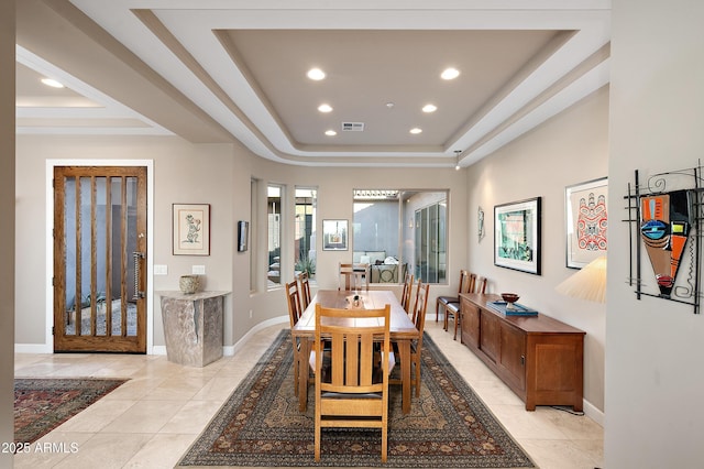 dining space featuring light tile patterned flooring and a raised ceiling